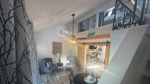 Un espacio habitable tipo loft con comedor, una escalera y una cocina visible a través de una puerta abierta.