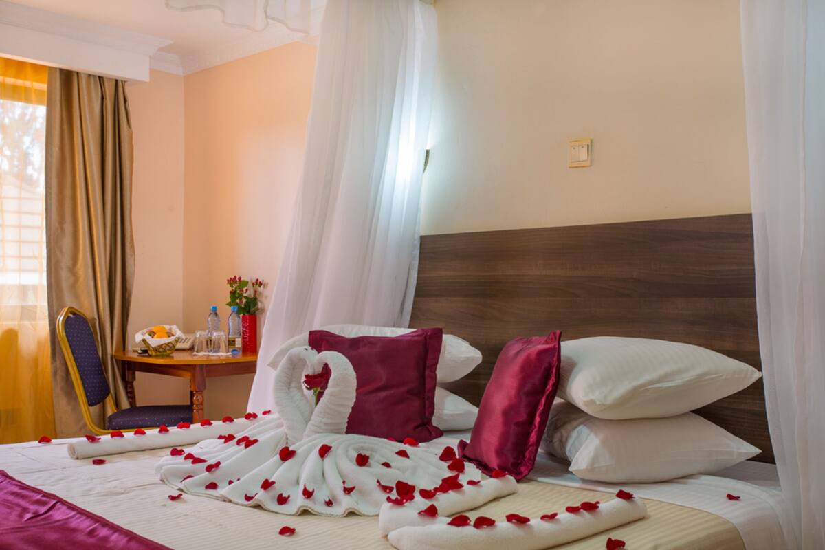 Ein Hotelzimmer mit Bett, Tisch mit Blumenvase und Stuhl.