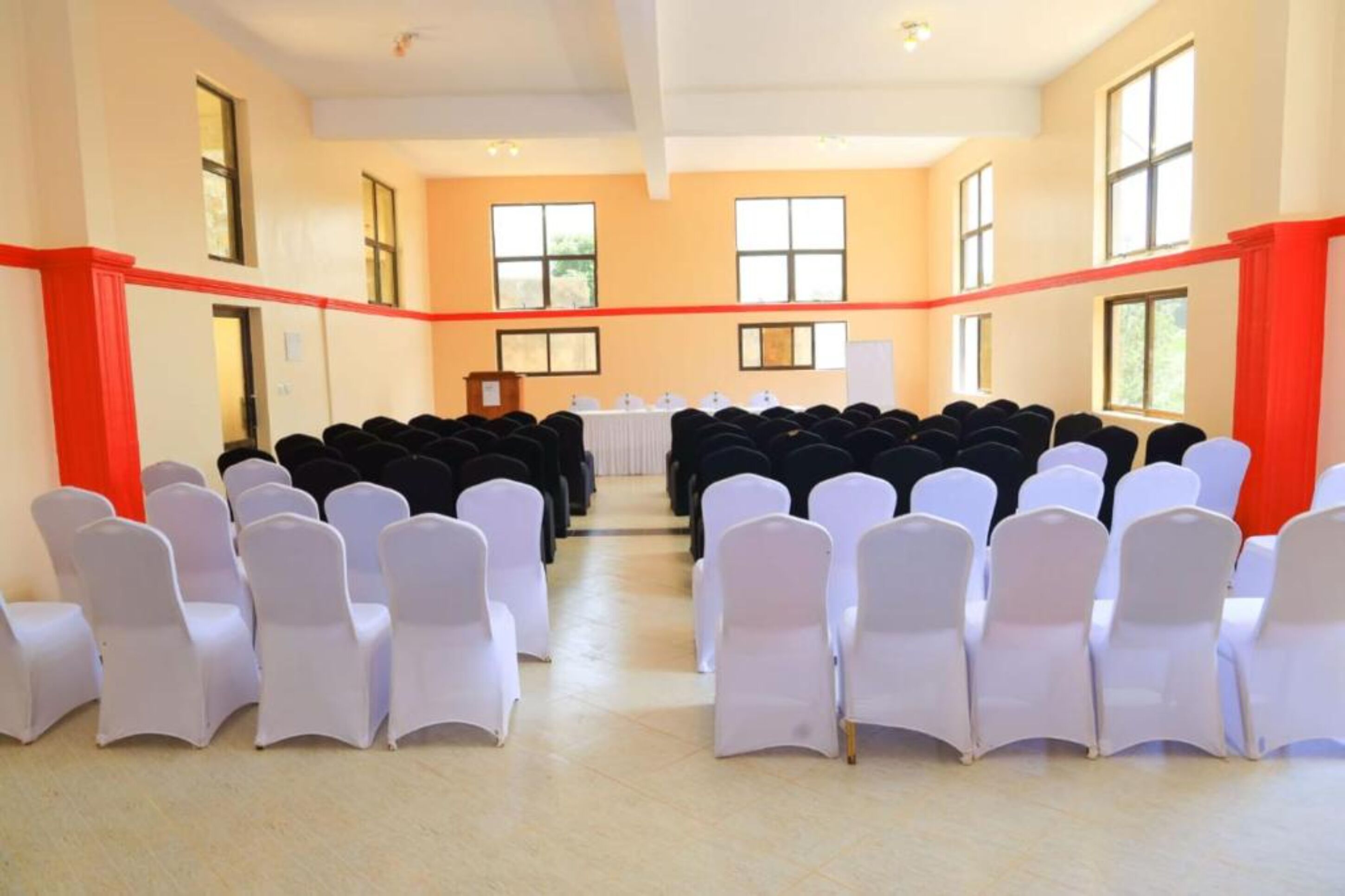 A conference room with rows of chairs, a podium, and large windows.