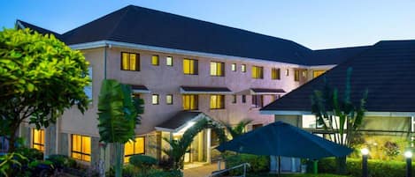 Stunning hotel with a symmetrical facade, surrounded by lush greenery and a covered entrance.