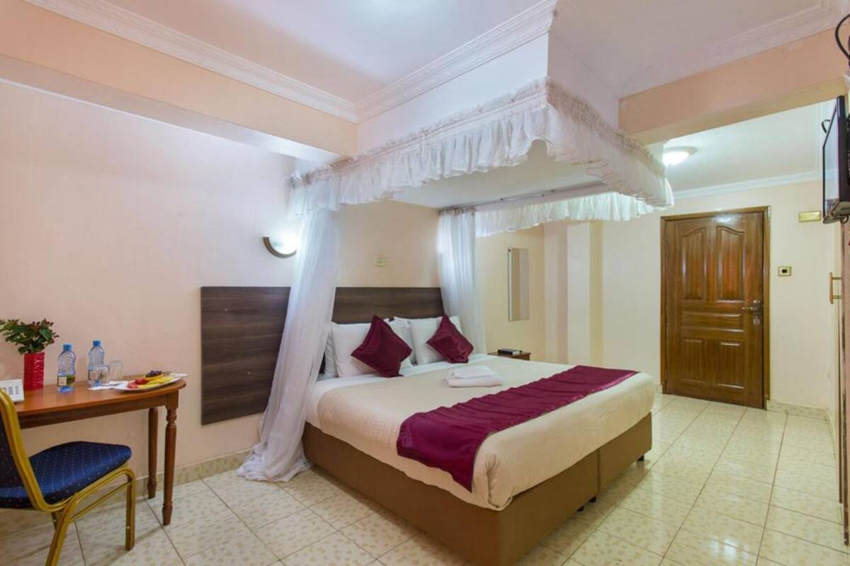 Ein Hotelzimmer mit Bett, Schreibtisch mit Stuhl, Nachttisch und Tür.