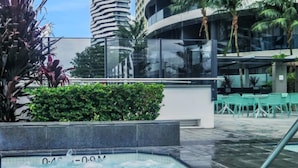Um hotel moderno com piscina no terraço, rodeado por vegetação exuberante e palmeiras.