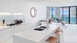 Cozinha moderna com ilha central, banquetas e vista da cidade por grandes janelas.