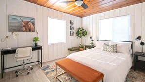 Une chambre à coucher comprenant un lit, un bureau, une chaise et un ventilateur de plafond.