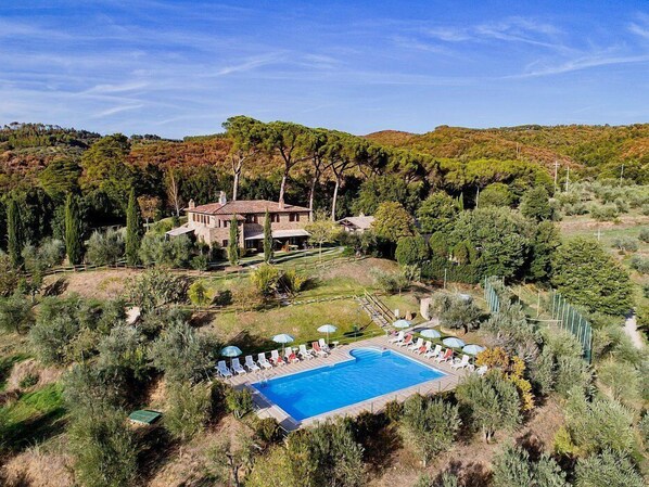 A large house with a swimming pool surrounded by trees.