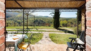 Eine Terrasse im Freien mit einem Essplatz, einem Stuhl und Blick auf eine üppige Landschaft.