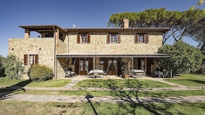 Una casa de piedra con un patio, mobiliario exterior y un cielo despejado.