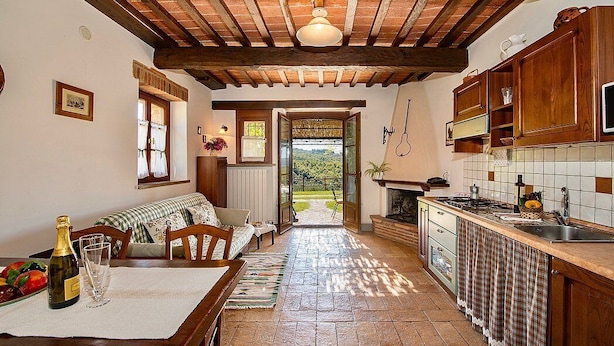 Una cocina rústica con vigas de madera, un comedor con banco y vistas al exterior.