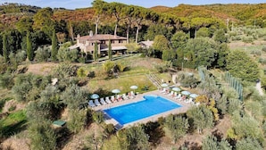 Una casa grande con piscina rodeada de árboles.