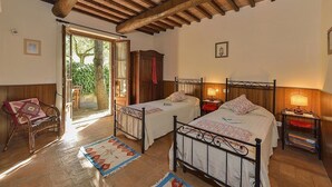 Ein Schlafzimmer mit zwei Betten, Holzbalken an der Decke, einem Holzschrank und einer Bank.