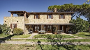 A stone house with a patio, outdoor seating, and a clear sky.