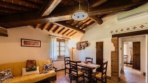 A cozy room with a wooden ceiling, a dining table with chairs, a sofa, and a radiator.