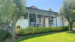 A covered outdoor area with a table and chairs, surrounded by greenery and trees. - Villa Bougainville: A welcoming one-story villa situated in a quiet location, a few minutes from the town center, with Free WI-FI. (Amaroni)