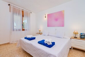 A hotel room with a bed, a nightstand, a lamp, and a painting on the wall.