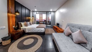 Una camera da letto moderna con un letto, un divano, una TV e un balcone con tende.
