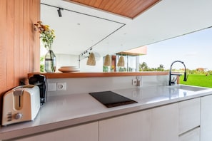 Enjoy a meal with a view from this kitchen, featuring a toaster and a large window overlooking a lush lawn.