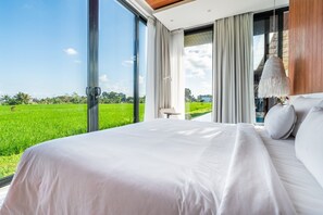 Enjoy a serene retreat with a large bed and stunning views of a lush green field from the large window.
