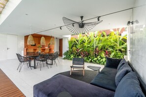 Relax in a sleek outdoor space with a comfortable seating area, dining table, and lush green surroundings.