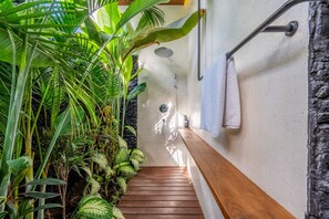 Staircase leads to a shower area surrounded by lush tropical plants.