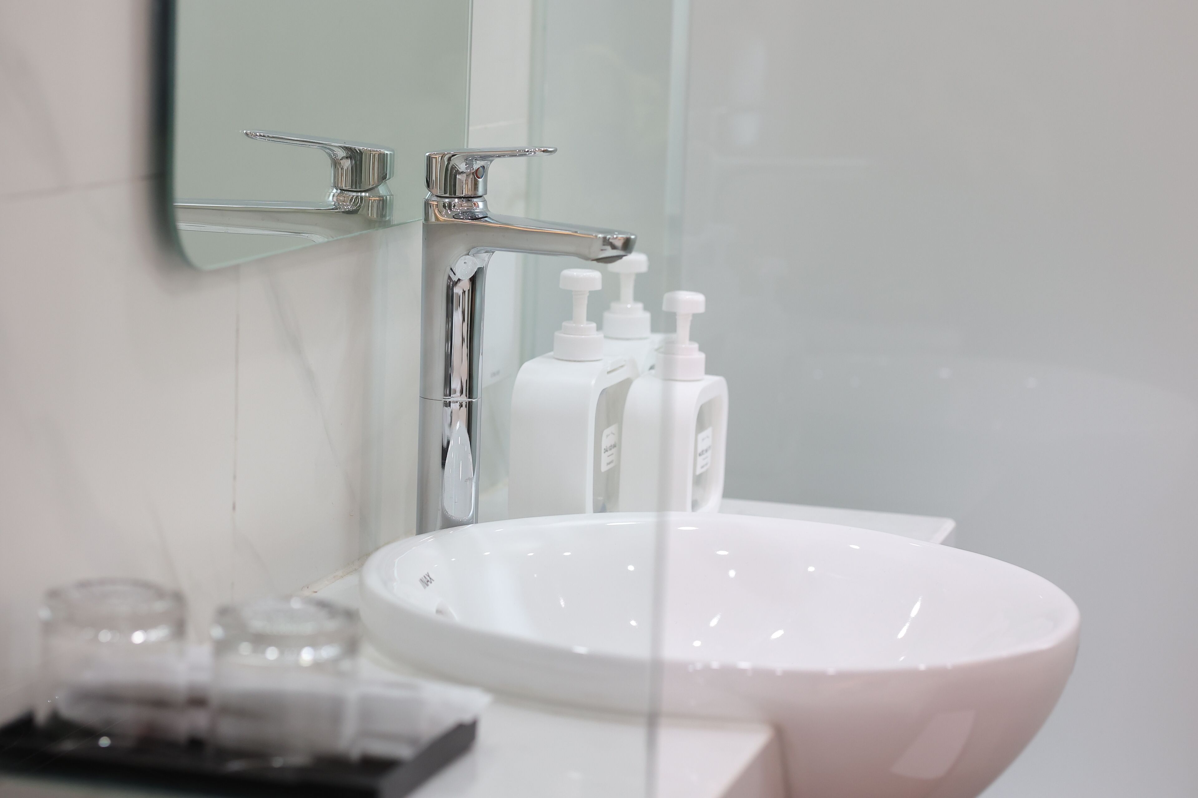 Une salle de bain avec un lavabo blanc, un miroir et deux distributeurs de savon.