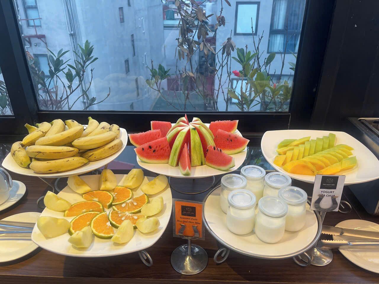 A breakfast buffet with various fruits and yogurt containers.