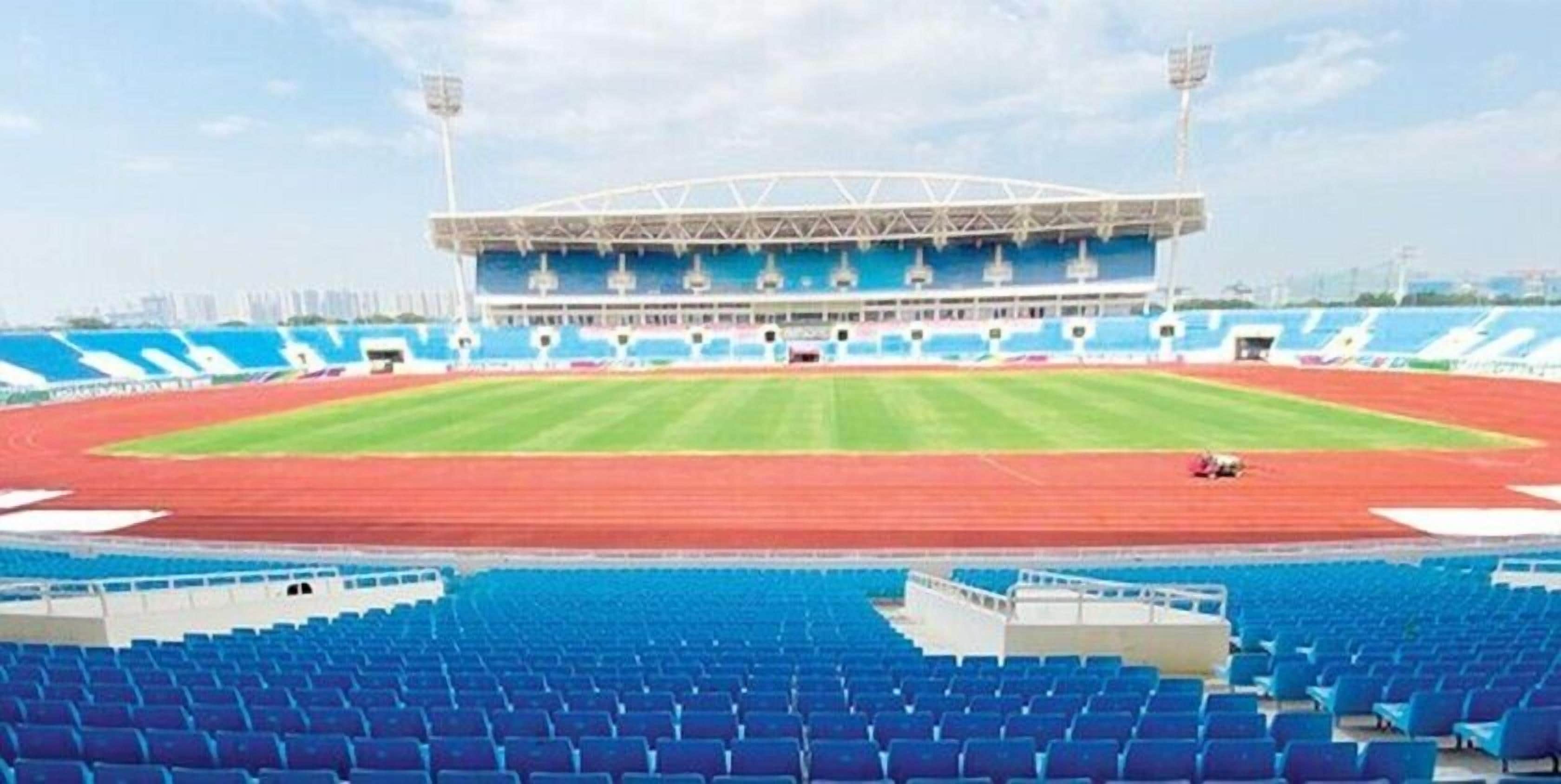 Un estadio con asientos azules, césped verde y una pista roja.