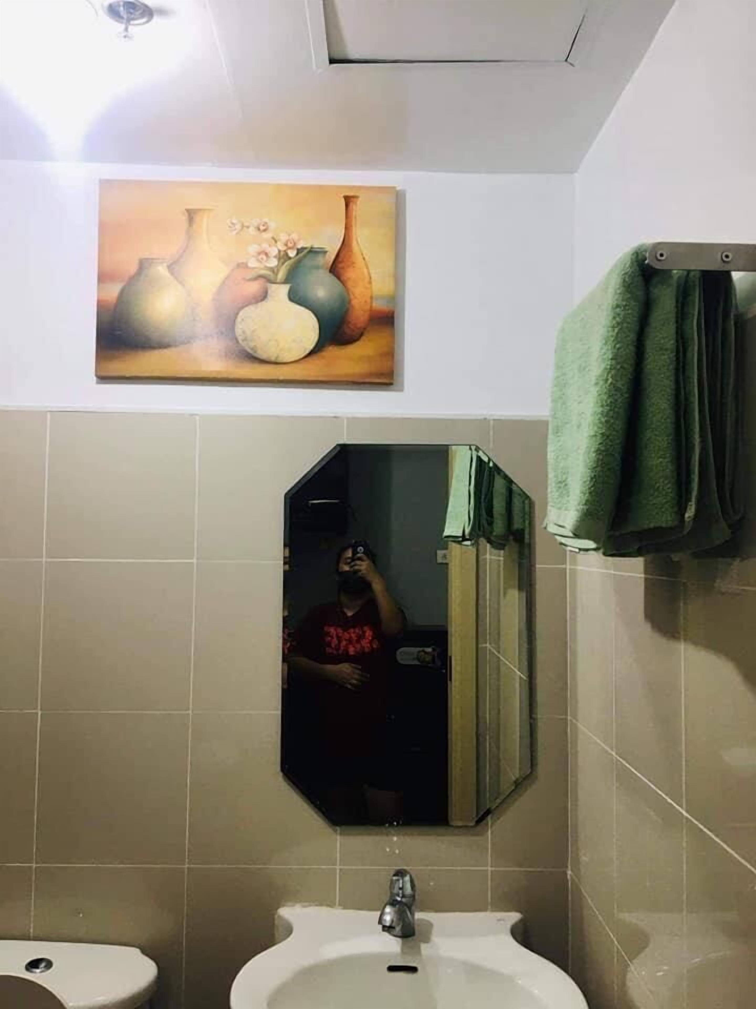 Une salle de bain avec un lavabo, un miroir et un tableau représentant des vases accroché au mur.