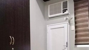 Une pièce avec une armoire en bois foncé, une porte blanche, une petite table et un appareil de climatisation fixé au mur.
