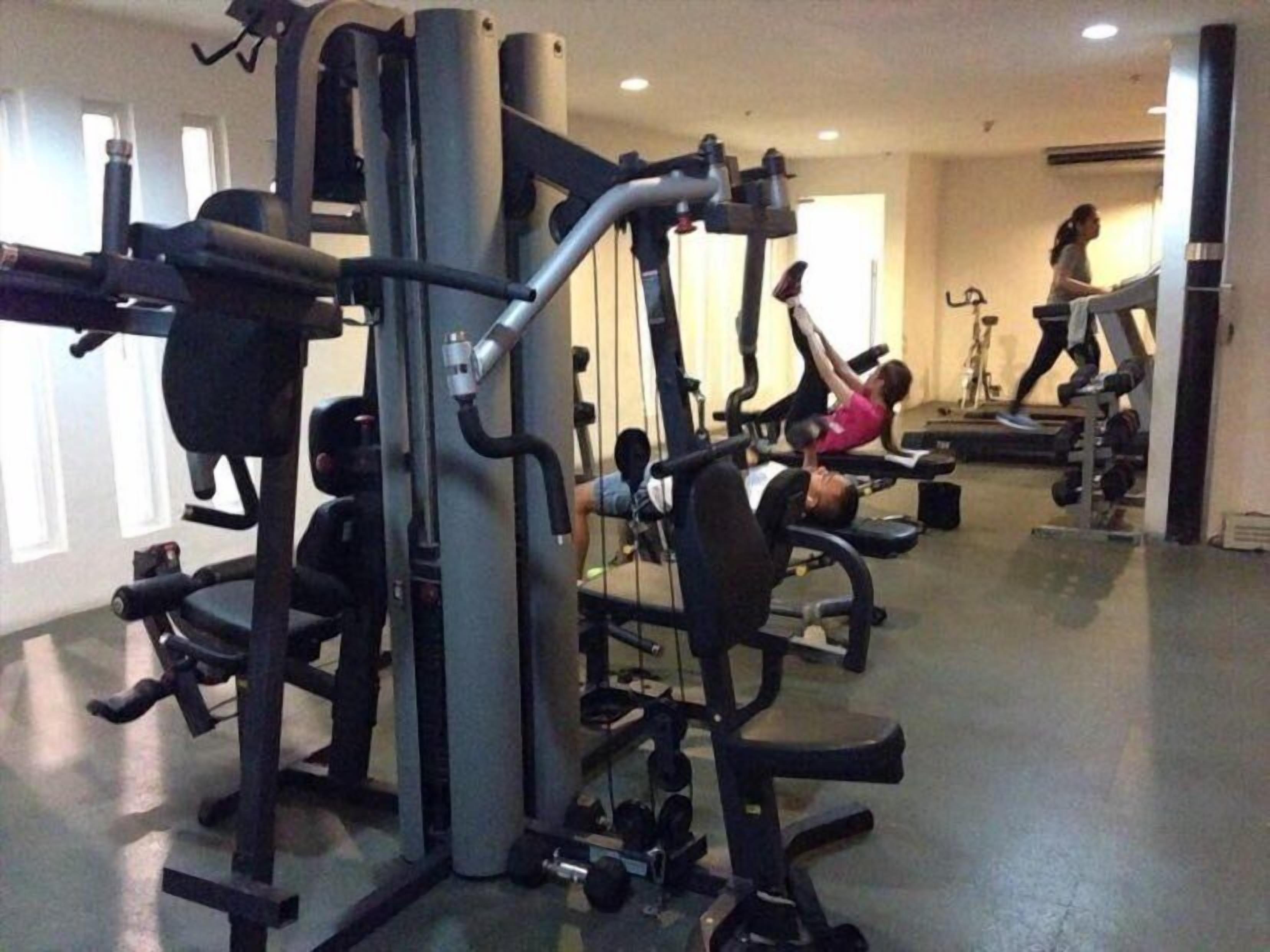 Un gimnasio con varias máquinas de ejercicio, incluyendo una prensa de banca y una prensa de piernas.
