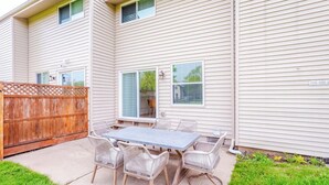 Ein zweistöckiges Haus mit einer Terrasse, komplett mit Tisch und Stühlen.