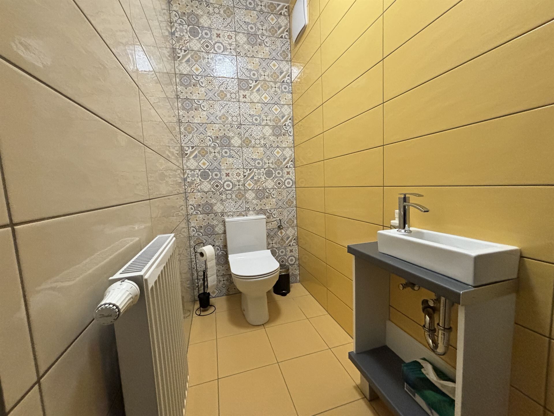 Un baño pequeño con inodoro, radiador y lavamanos.