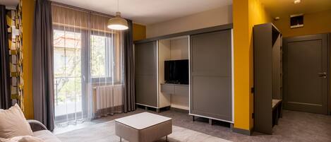Una sala de estar moderna con un sofá, un reposapiés y un televisor en un mueble empotrado.