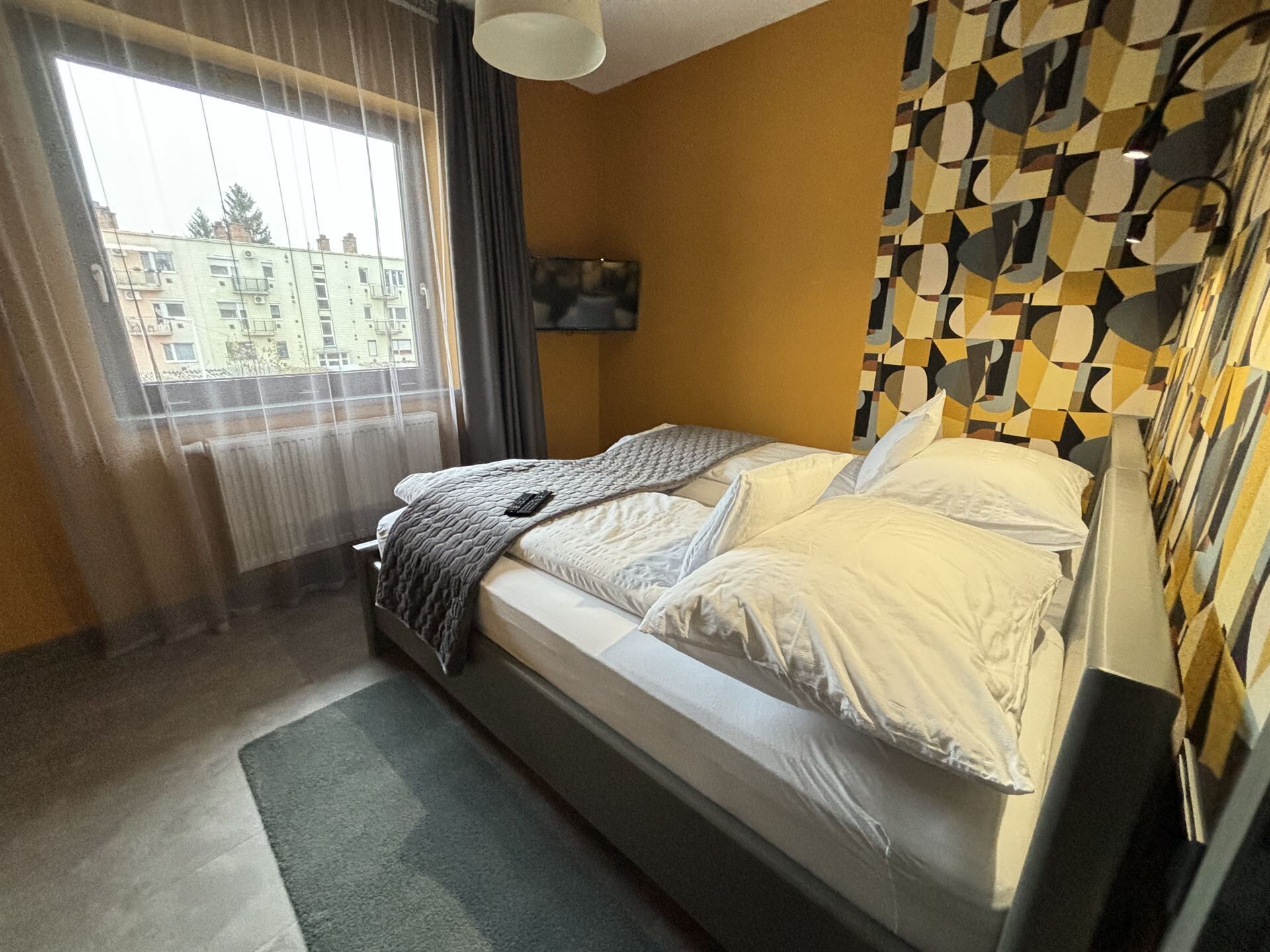Un dormitorio con cama, ventana y un papel tapiz decorado.