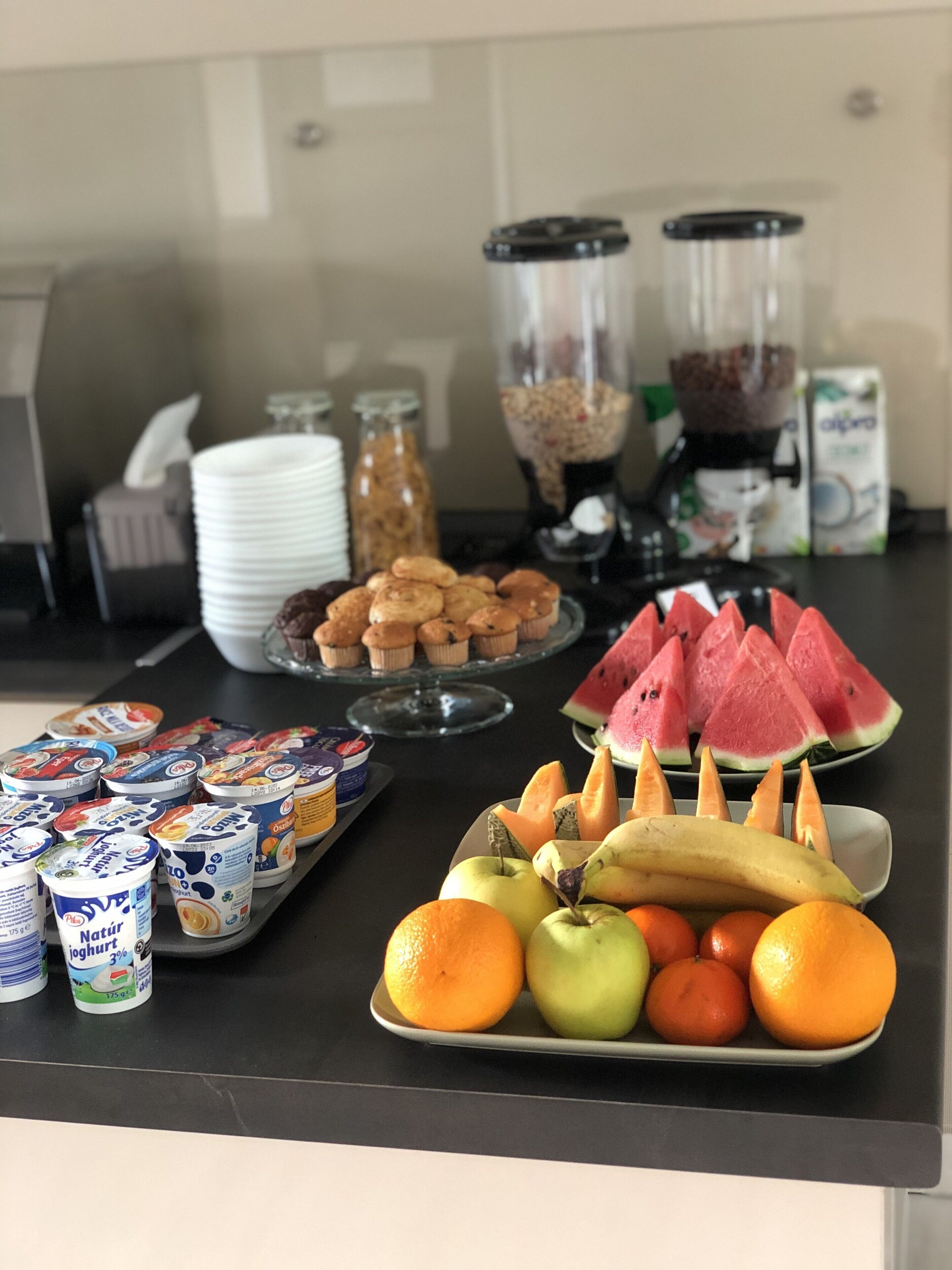 A buffet table with various food items including fruits, yogurt, and pastries.