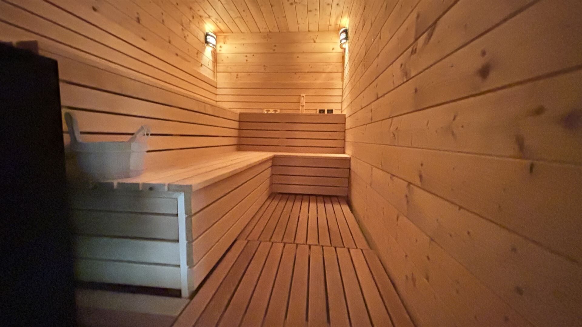 Un cuarto de sauna con paredes y bancos de madera, equipado con luces empotradas.