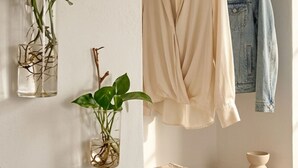 Un armario con ropa colgada, un estante con una cesta de mimbre y dos plantas en macetas.