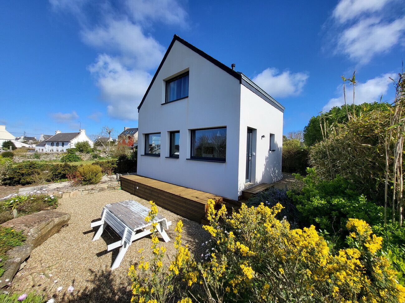 A modern two-story house with a white exterior and a wooden deck.