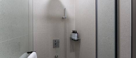 A modern bathroom with a shower, a towel rack, and a soap dispenser on the wall.