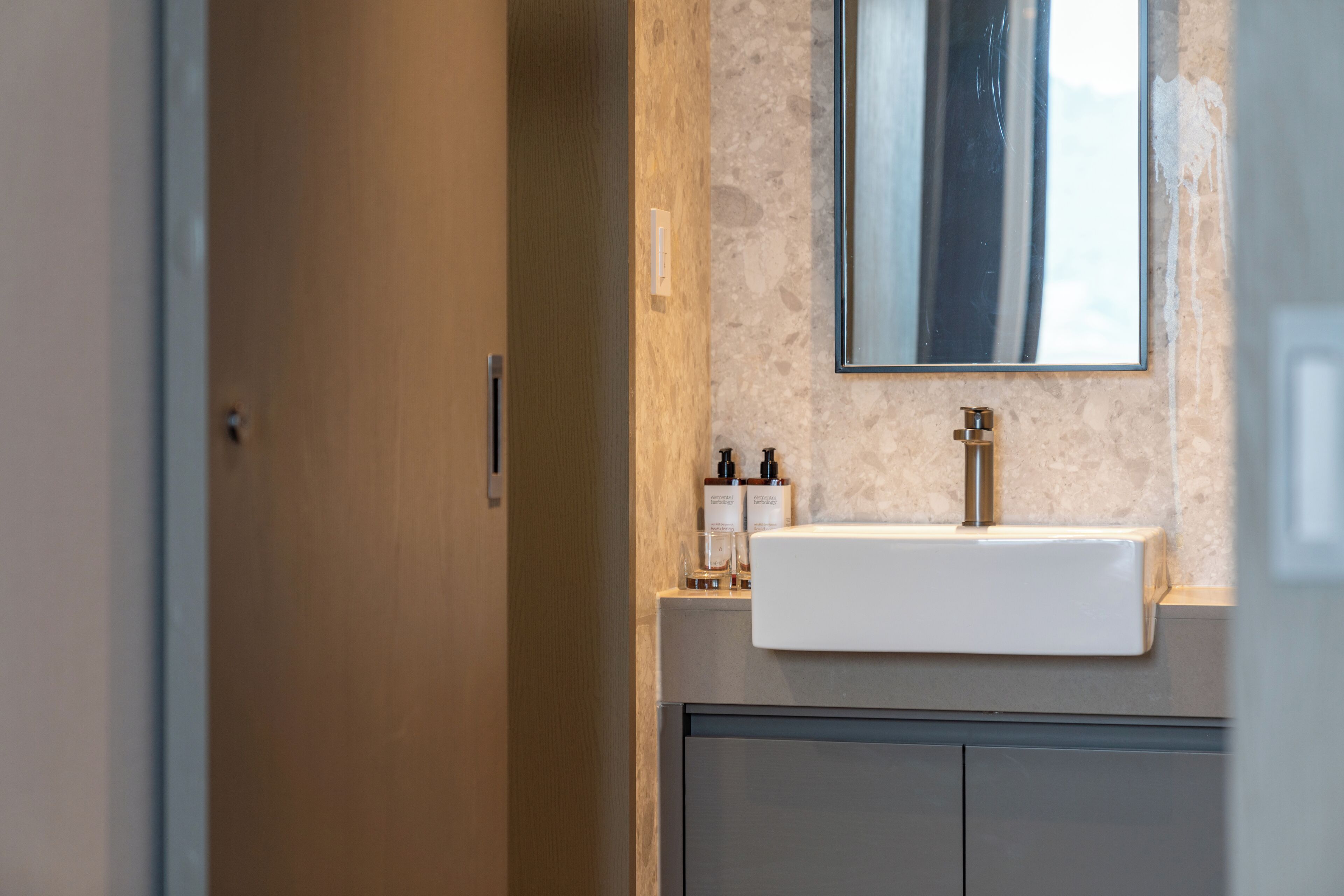 A bathroom with a white sink, a mirror, and toiletries on the counter.