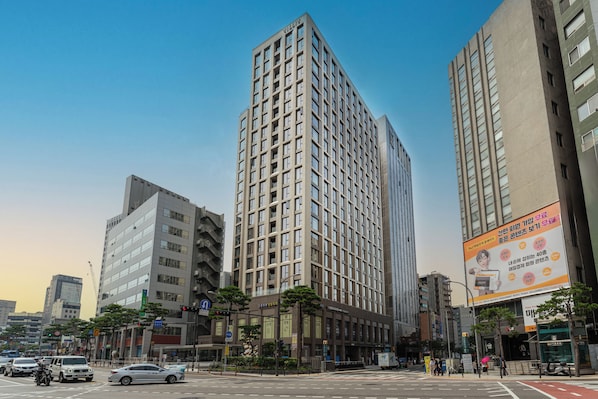 Un immeuble moderne de grande hauteur, doté d’une façade en verre remarquable, situé dans un environnement urbain, entouré d’autres bâtiments imposants.