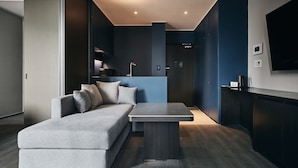Una sala de estar moderna con un sofá seccional gris, una mesa de centro de madera oscura y un televisor de pantalla plana montado en la pared.