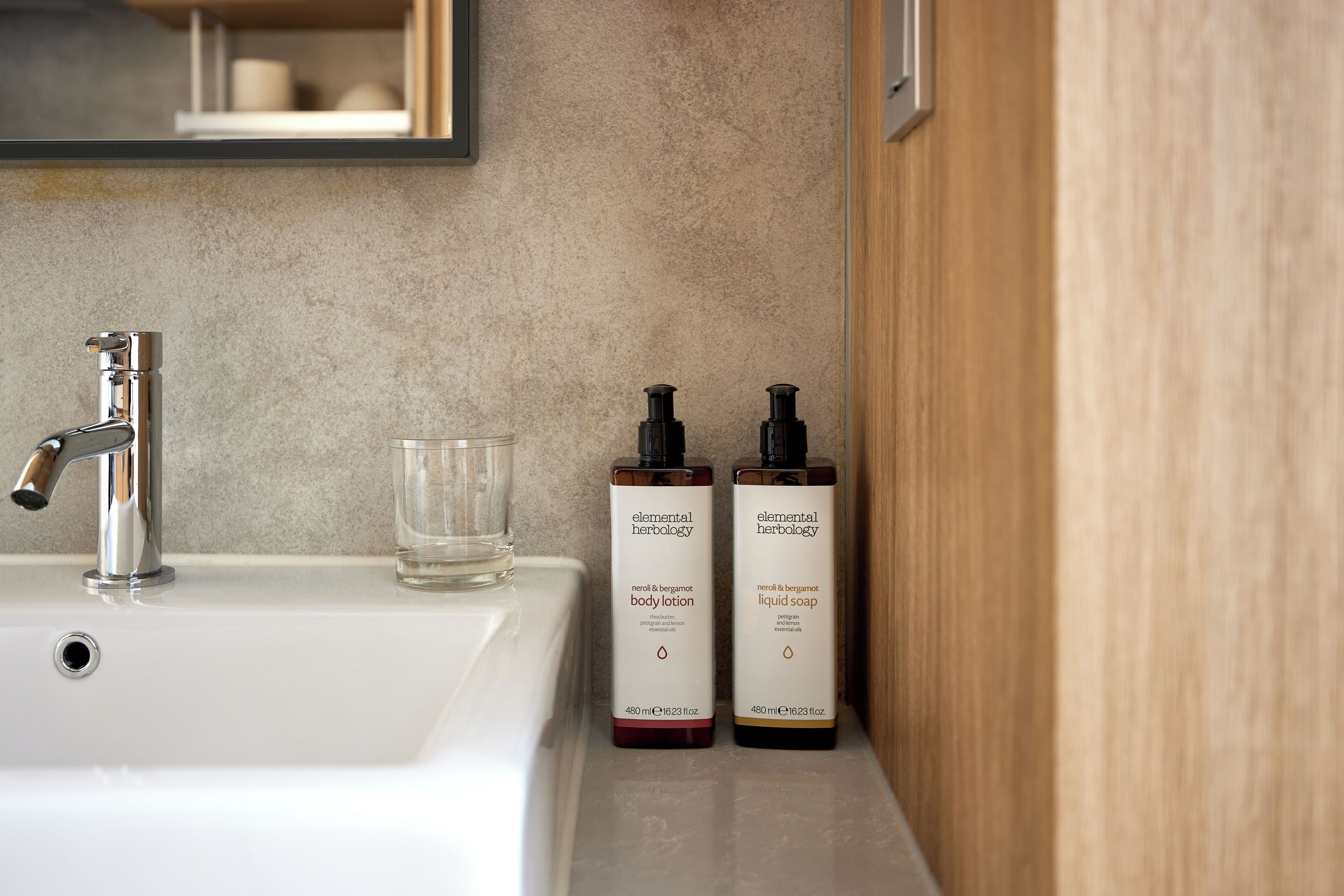 Un lavabo in bagno con due prodotti Elemental Herbology, un bicchiere e uno specchio.