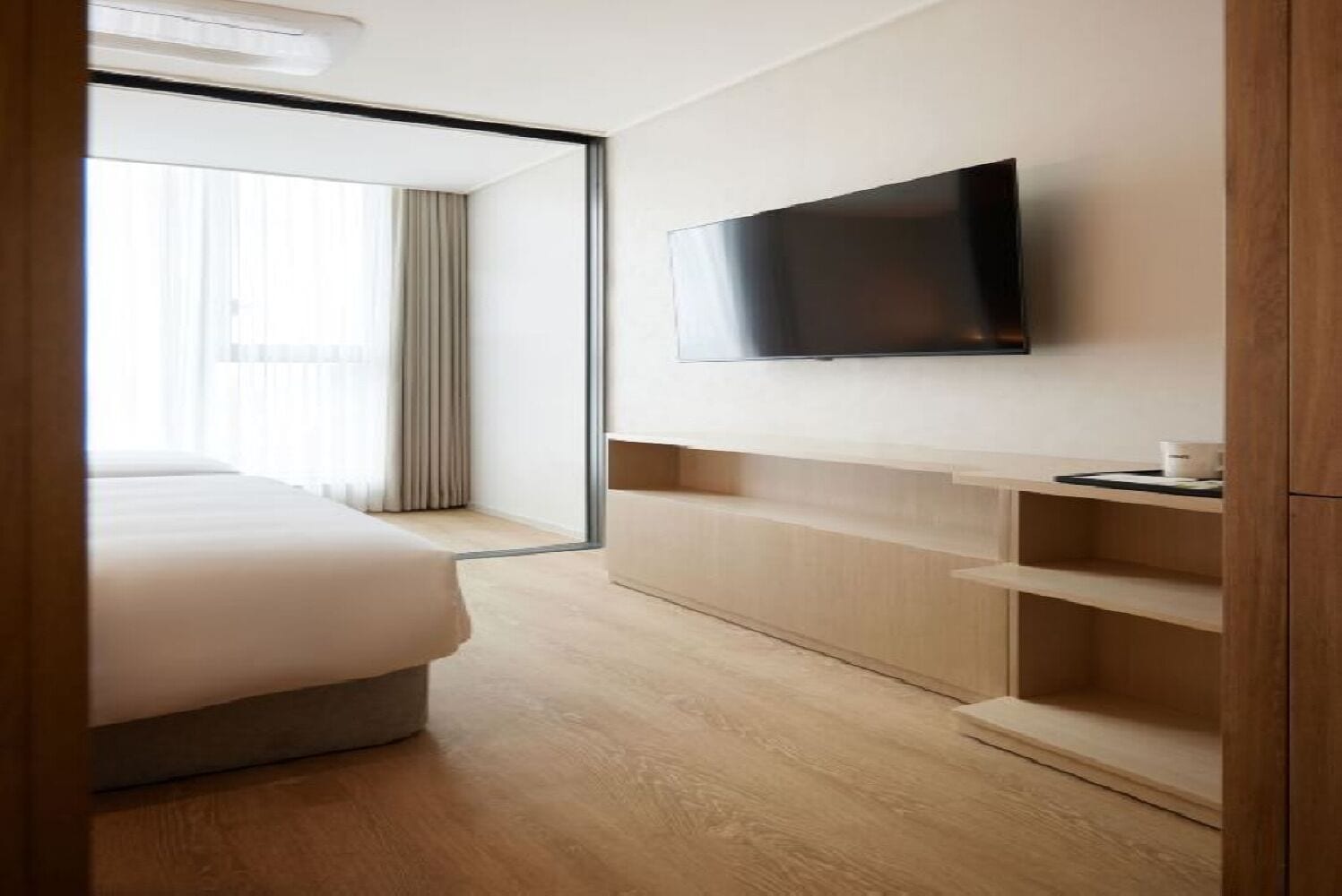 Ein Hotelzimmer mit einem Bett, einem an der Wand befestigten Fernseher und einem Holzschrank.