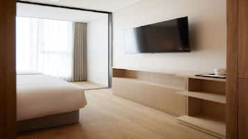 Ein Hotelzimmer mit einem Bett, einem an der Wand befestigten Fernseher und einem Holzschrank.