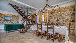 Ein Essbereich mit einer Steinwand, einer Holztreppe und einem grünen Sofa.