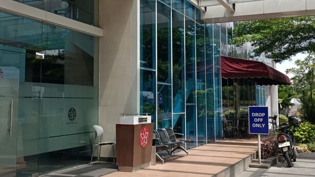 A modern building with a glass facade, a red awning, and a 'Drop Off Only' sign. - EXPRESS O 92140 Appartel (Bekasi)