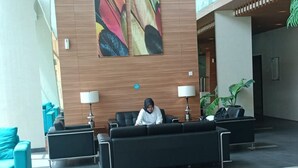A spacious lobby with a large abstract painting on the wall, a seating area with tables, and a potted plant. - EXPRESS O 92140 Appartel (Bekasi)