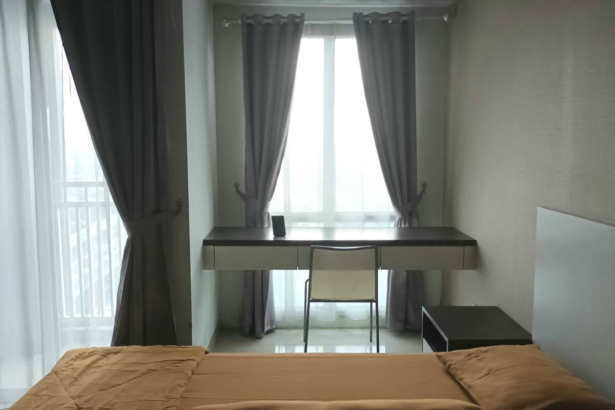 A hotel room with a bed, a desk, and a chair.