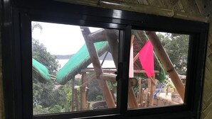 Finestra amb vista a una estructura de fusta amb teulada verda i una bandera rosa.