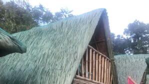 Una construcció tradicional de bambú amb teulada de palla i escala de fusta que condueix a un balcó.